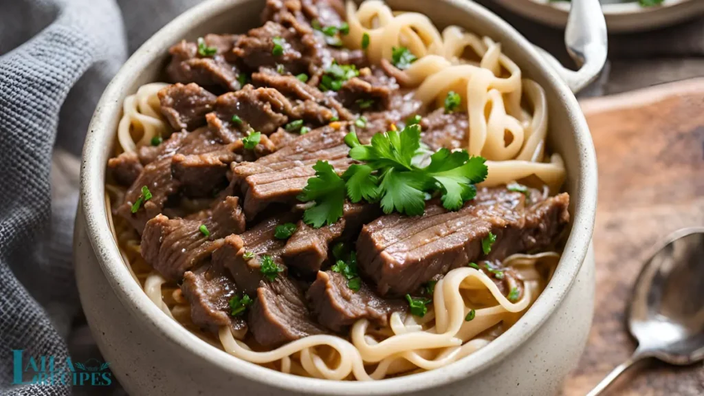 Ladle pouring beef broth over noodles.