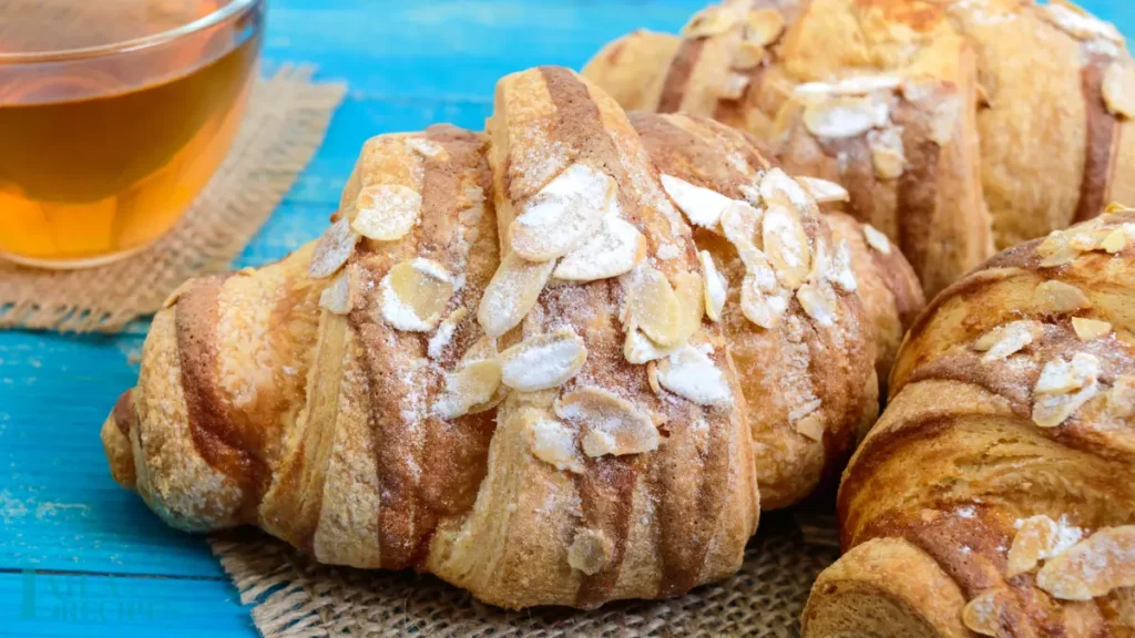 A plate of golden almond croissants served with coffee.
