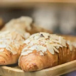 Close-up of a flaky almond croissant topped with sliced almonds.