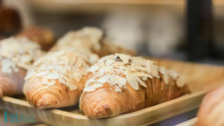 Close-up of a flaky almond croissant topped with sliced almonds.