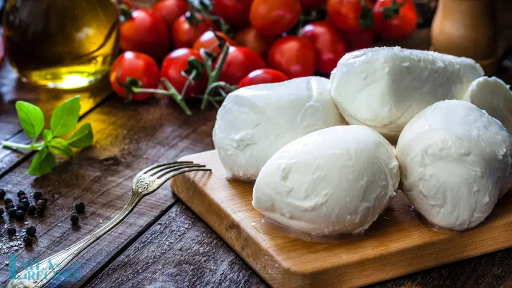 Hands stretching soft curds into over a wooden countertop.