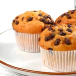 Freshly baked chocolate chip muffins on a cooling rack.