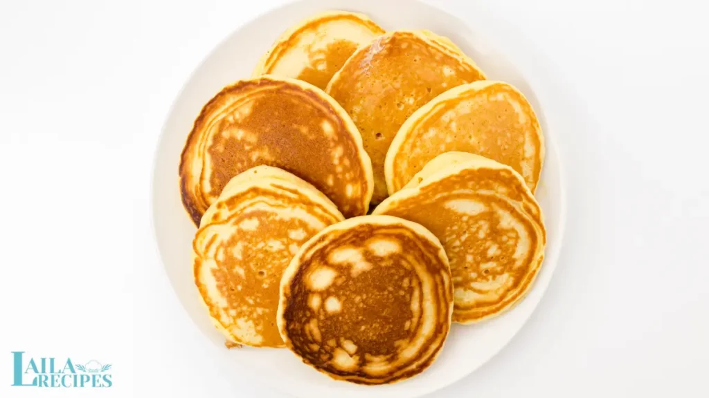 A stack of golden treats topped with fresh fruit and syrup.