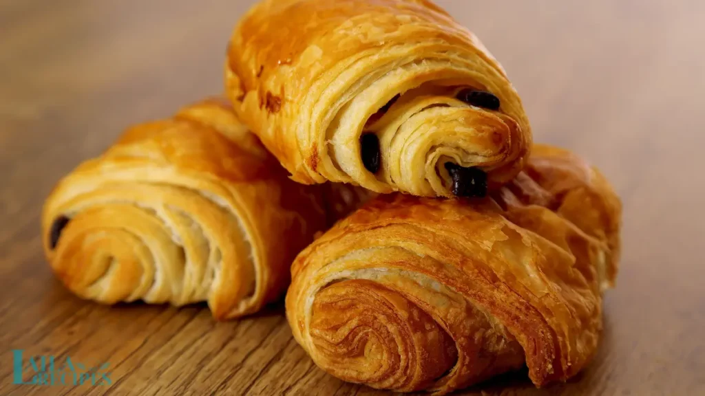 Homemade chocolate croissants cooling on a rack.
